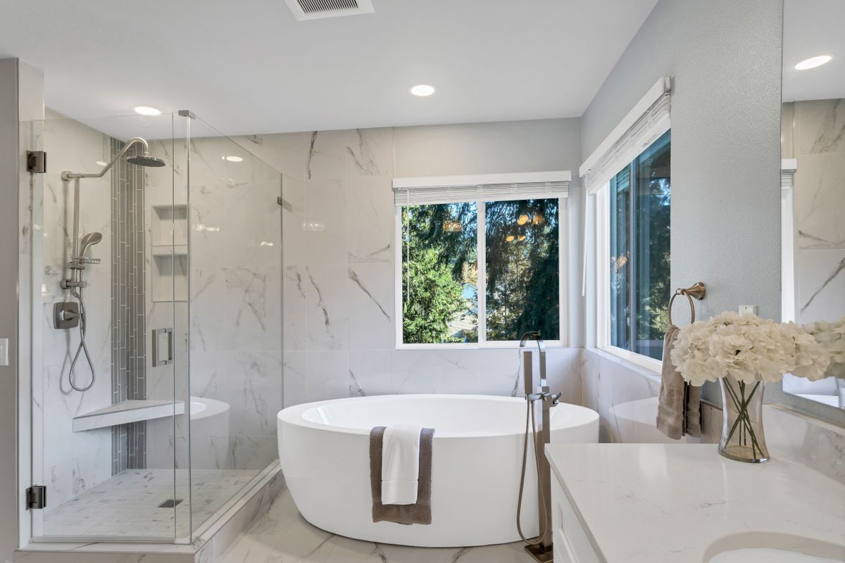 Baño moderno con ducha de obra y bañera exenta, revestimiento de mármol